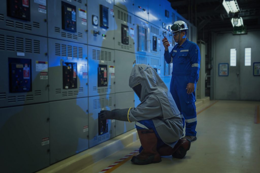 Two electrical engineers testing in a switchroom, wearing Arc Flash PPE