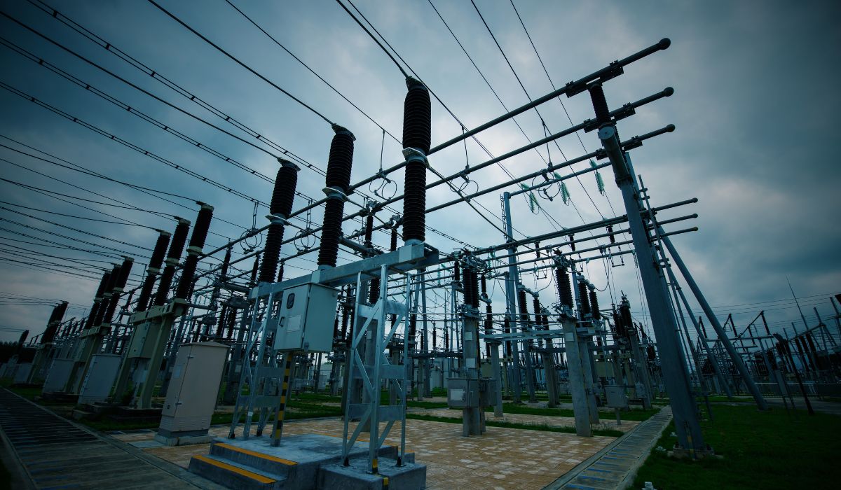 A low angle view of an electrical substation with the overlayed text "transmission & distribution"